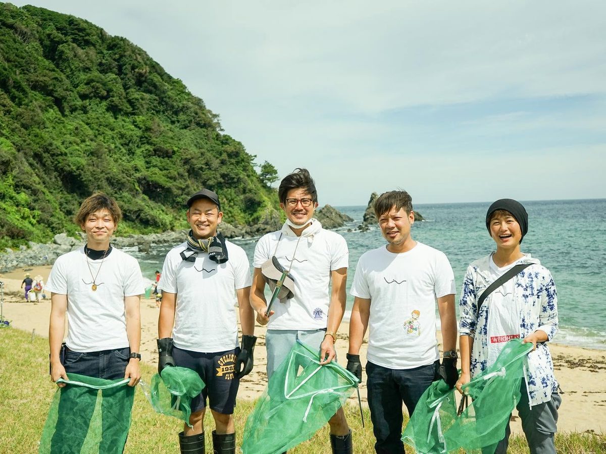 海岸で、ゴミ拾い用の網を持って並ぶシーソンズのメンバー5人